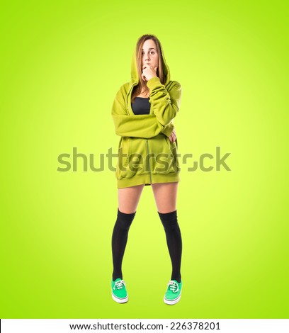 Pretty young girl wearing urban style thinking over green