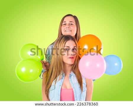 Friends with many balloons over green background