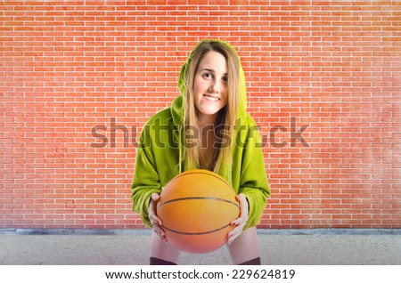 Blonde girl playing basketball over textured background