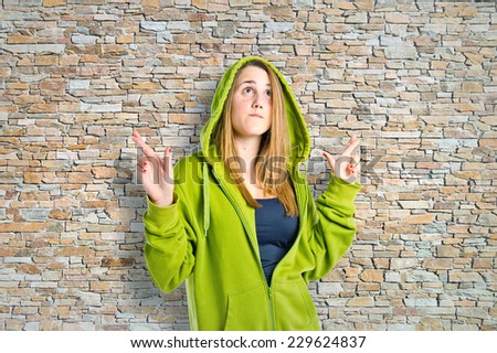 Pretty girl with her fingers crossing over textured background