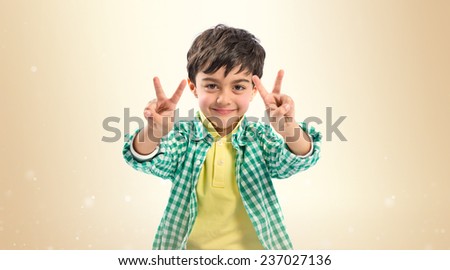 Boy making a victory sign over ocher background