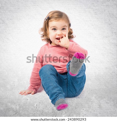 Cute girl sitting and laughing over textured background