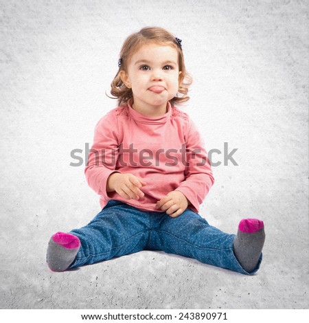 Cute baby girl sticking out tongue over textured background