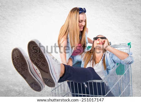 Girls playing with supermarket cart over textured background