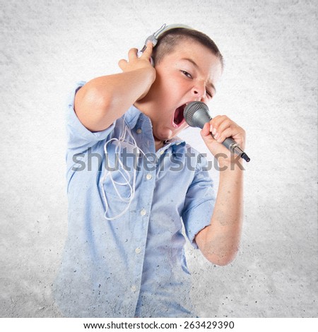 Brunette kid listening and singing music over textured background