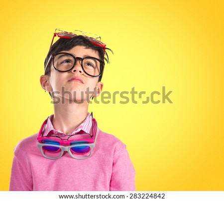 Boy thinking with many glasses over colorful background