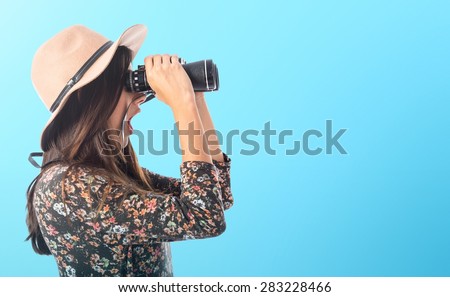 Surprised woman with binoculars over colorful background