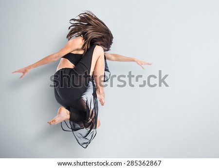 Young fitness female jumping over textured background