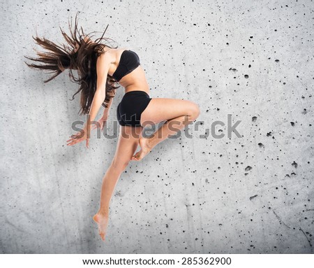 Young fitness female jumping over textured background