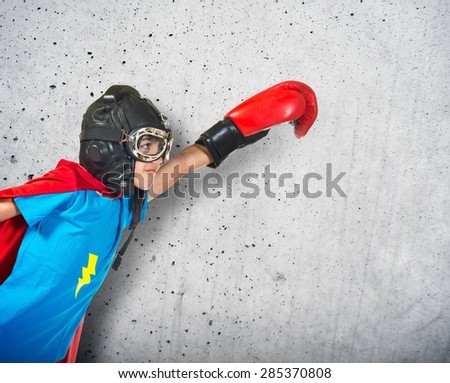 Child dressed like superhero with boxing gloves over textured background