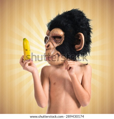 Child with monkey mask showing his banana
