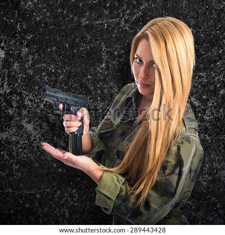 Military woman carrying a gun over textured background