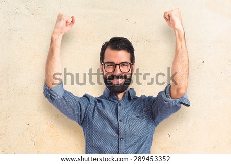 Lucky young hipster man over textured background