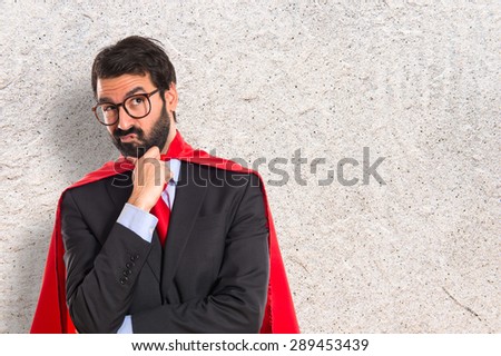 Businessman dressed like superhero thinking over white