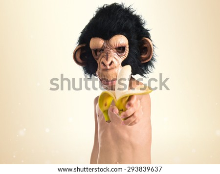Child with monkey mask holding a banana over ocher background