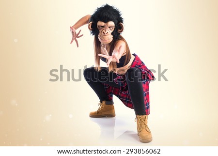 Woman with monkey mask dancing over ocher background