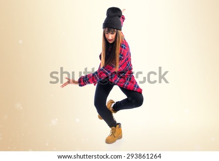 Young woman dancing street dance over ocher background