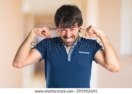 Man covering his ears inside house