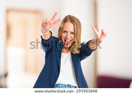 Woman doing victory gesture inside house