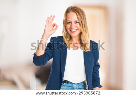 Woman making Ok sign inside house