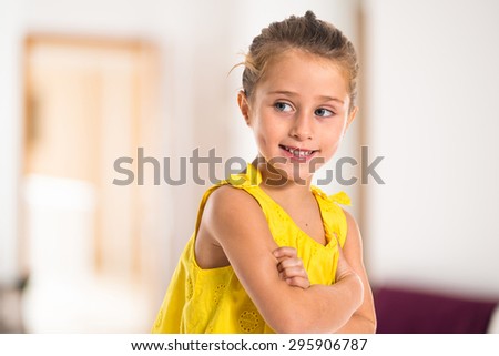 Blonde little girl walking with her arms crossed inside house