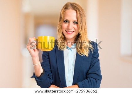 Blonde girl holding a cup of coffee inside house