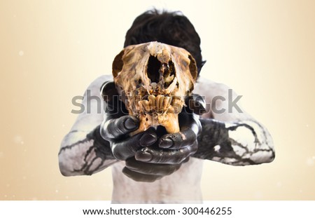 Primitive man offering a rabbit skull over ocher background