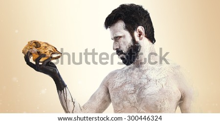 primitive man looking a rabbit skull over ocher background