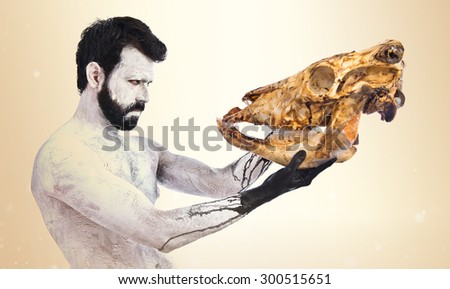 prehistoric man looking veal skull over ocher background