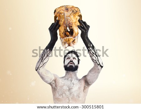 Primitive man offering veal skull over ocher background