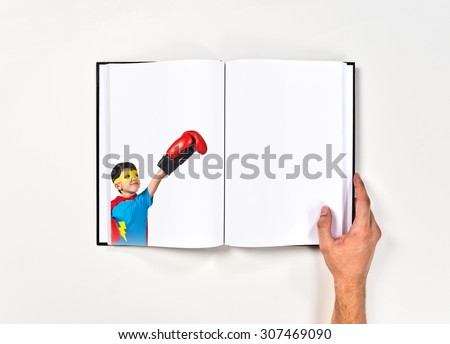 Child dressed like superhero with boxing gloves printed on book