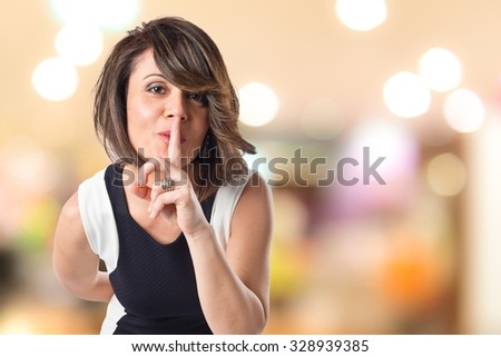 Pretty woman making silence gesture on unfocused background