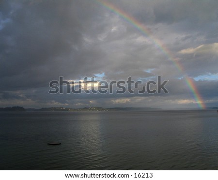 Rainbow over the southern end of Puget Sound, taken from Home (Lakebay), Washington, looking southeast towards Mount Rainier, which is hidden behid the clouds in the center. Landscape orientation.