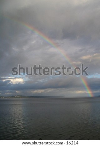 Rainbow over the southern end of Puget Sound, taken from Home (Lakebay), Washington, looking southeast towards Mount Rainier, which is hidden behid the clouds in the center. Portrait orientation.