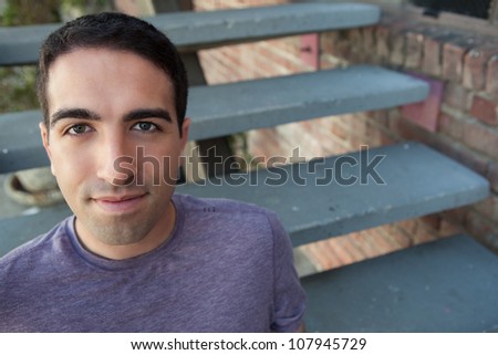 Serious young man on stairs outdoors looking at camera with serious expression