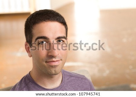 A serious young good looking guy looking at camera indoors wearing a purple shirt