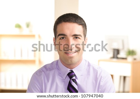 Attractive young business man looking at camera with smile wearing a purple shirt and tie.