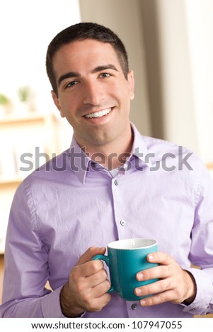Happy good looking guy holding a coffee mug smiling and looking at camera with purple shirt