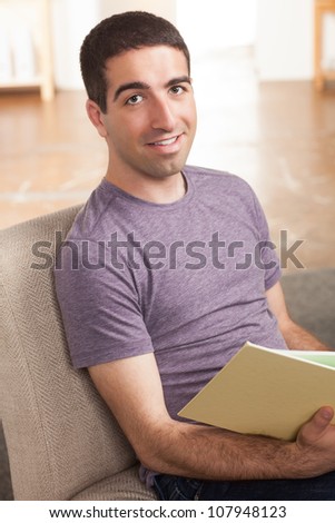 Good looking guy reading a book and looking at camera with smile.