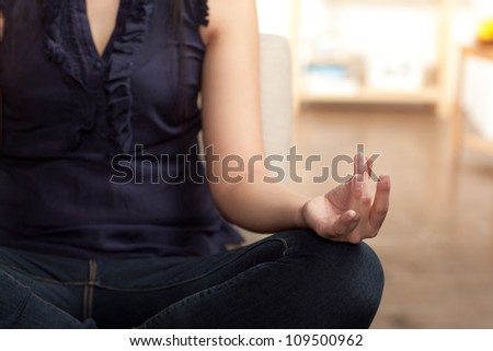 Young Asian woman sitting crossed legged in a meditation posture.