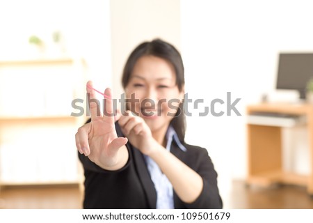 Cute Asian female having fun at work with rubber bands wearing a black suit and blue shirt.