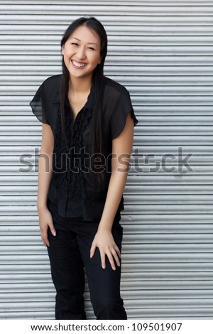 Attractive Asian woman outdoors wearing short sleeved black shirt and black pants