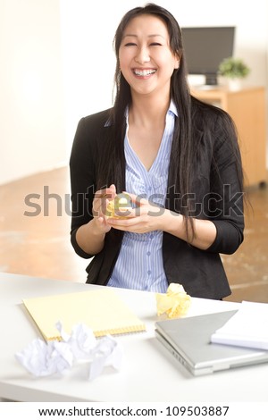 Attractive Asian woman at work in office setting with straight black hair wearing black suit and blue shirt
