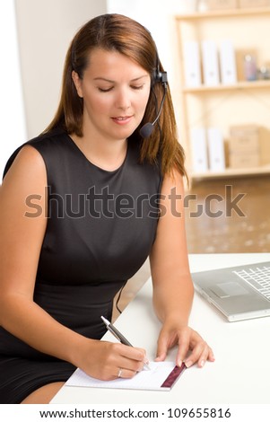 Beautiful Caucasian female at work wearing a sleeveless black dress with brunette hair.