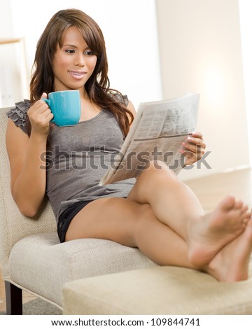 Beautiful Hispanic woman relaxing at home wearing short sleeve gray shirt and shorts.