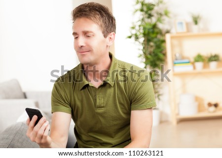 Cute Caucasian man relaxing at home in the living room with light hair wearing a green shirt and jeans.