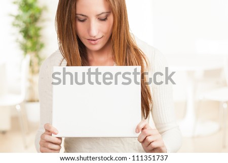 Beautiful young woman wearing white sweater with blank white sign.