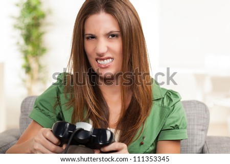Attractive young woman relaxing at home playing a game holding controller sitting on couch.