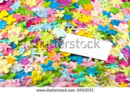 A white business card on a bed of spring colored flowers.