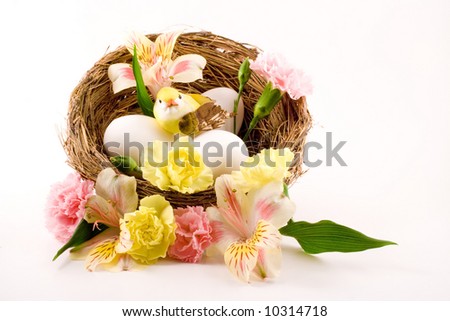 A lovely arrangement of eggs, flowers, a birds nest and a little yellow bird.